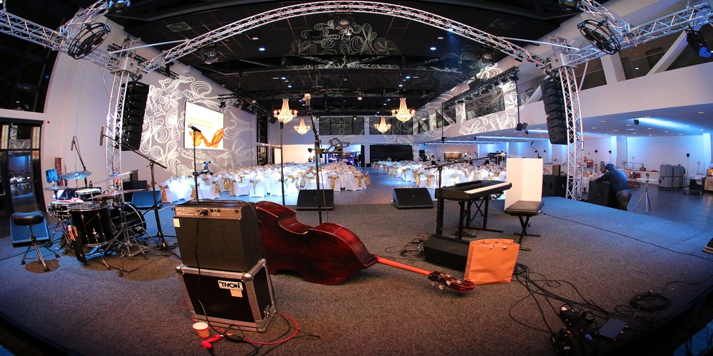 Gro&szlig;er Veranstaltungsraum mit B&uuml;hne, Musikinstrumenten und festlich gedeckten Tischen im Hintergrund