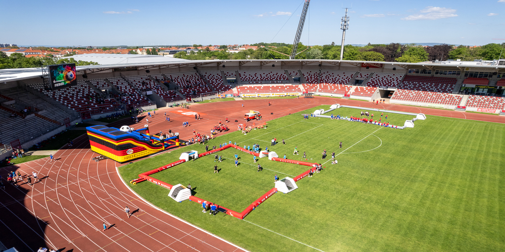 Drohnenaufnahme: Luftaufnahme des Steigerwaldstadions mit einer gro&szlig;en bunten H&uuml;pfburg und mehreren kleinen Fu&szlig;ballfeldern auf der Laufbahn und dem Rasen