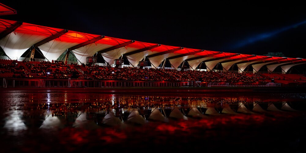 Westtrib&uuml;ne des Steigerwaldstadions mit Publikum bei Nacht mit roter Beleuchtung und Publikum, Spiegelung im Wasser davor