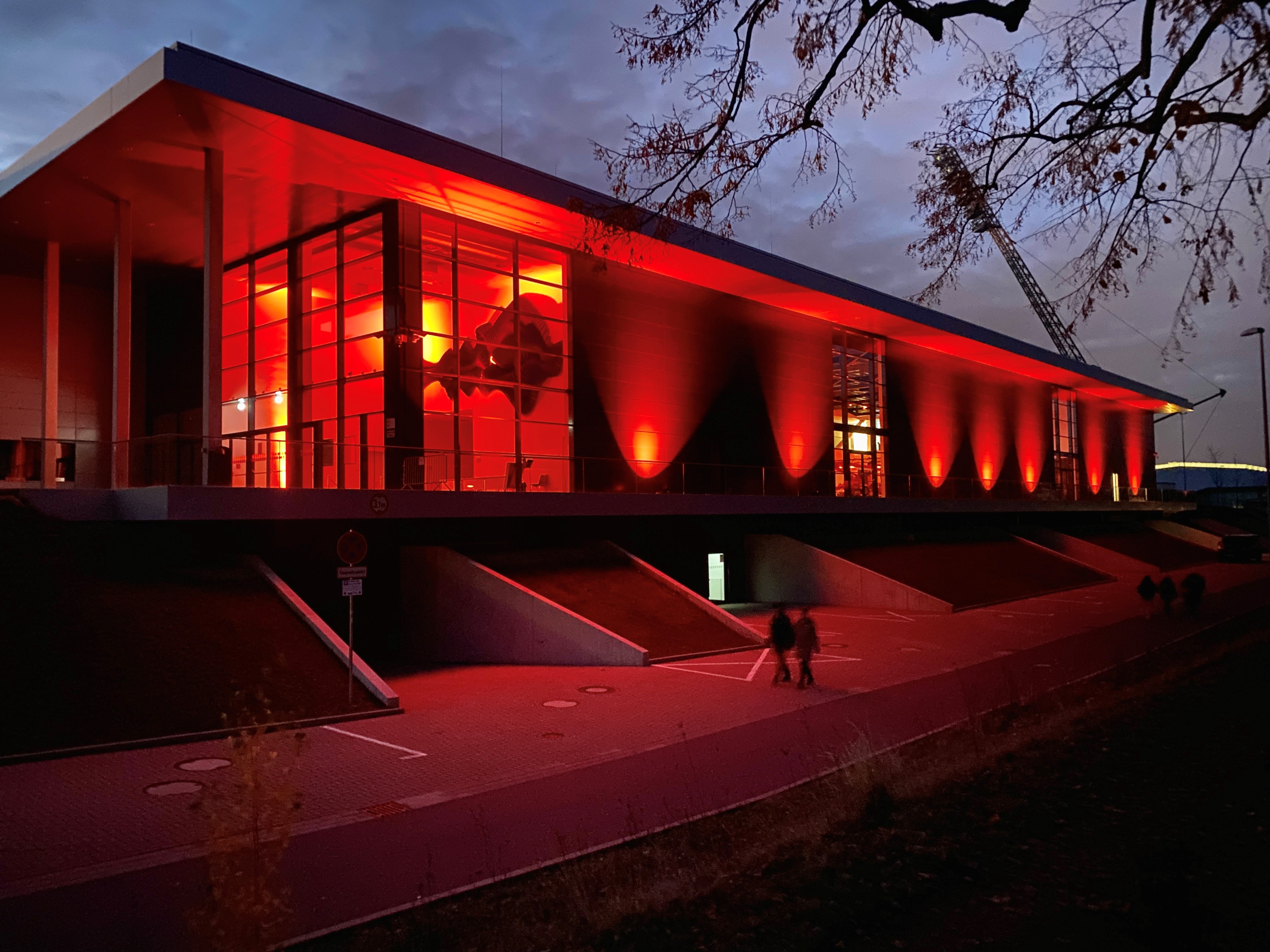 Orange beleuchtetes Hauptgebäude des Steigerwaldstadions bei Nacht.